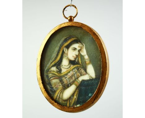 AN INDIAN MINIATURE OVAL PORTRAIT OF A FEMALE FIGURE on ivory, encased within a gilt metal frame and glazed, 7cm x 5.5cm.