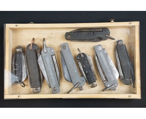 A collection of eight British military issued jack knives to include Army and Navy examples, housed within a wooden case. 
