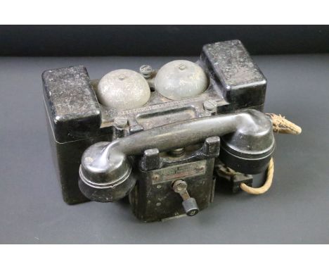 A British World War Two wind up field telephone, bakelite housing stamped with the British broad arrow. 