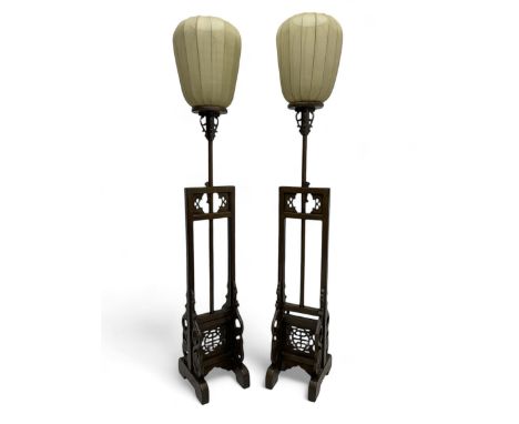 Pair of 20th century Chinese-design standard lamps, each with cream silk lantern shade, raised on a carved hardwood frame wit