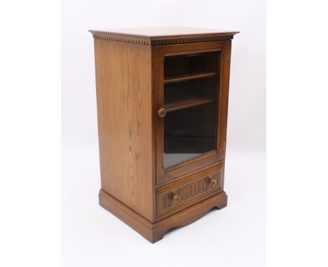 An Ercol elm hi-fi cabinet - with dentil frieze over a glazed door enclosing two shelves, above a base drawer, on bracket fee