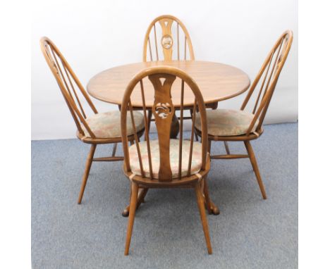 An Ercol Windsor elm extending dining table and four swan-back Windsor dining chairs - the table with oval top and single add