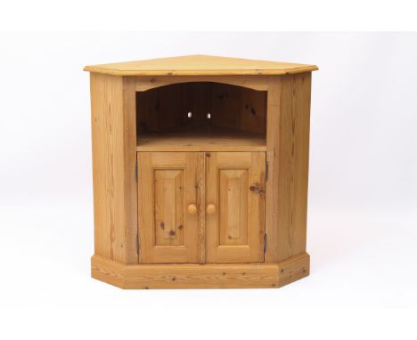 A pine corner cabinet - with an open shelf over a pair of panelled doors enclosing a cupboard with single shelf, on a plinth 