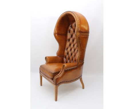 A Georgian-style tan leather and walnut porter's chair - the shaped, hooded back with brass studded leather panels, enclosing