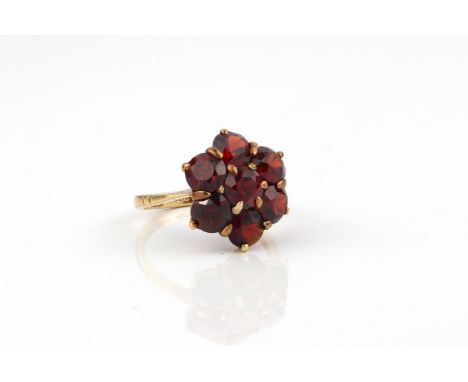 A 9ct rose gold and garnet cluster ring - stamped '9CT', with a floral cluster of seven round cut garnets, size H (gross weig