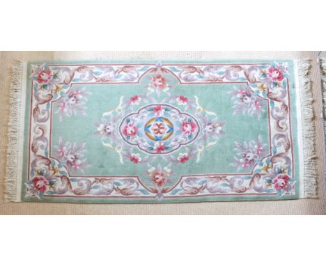 A Chinese floral wool rug - late 20th century, with a large floral medallion and spandrels on a light green ground, with a pa