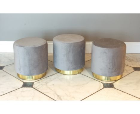 A set of three drum-form stools - modern, upholstered in light-grey, on gilt bases, 38 cm diameter, 40 cm high.