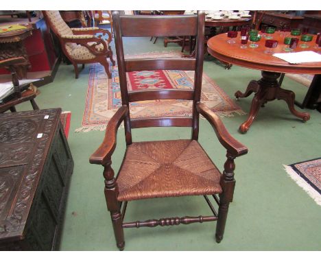 A 19th Century beech four ring ladder-back country elbow chair the rush seat over turned legs and stretcher stamped "E" to re