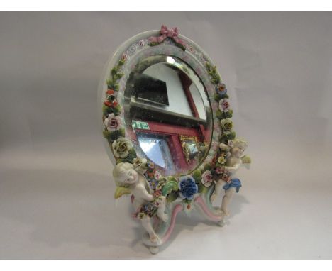 A Meissen style ceramic easel back mirror with cherub and floral detail