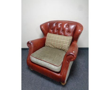 A red button leather and cloth wingback armchair 
