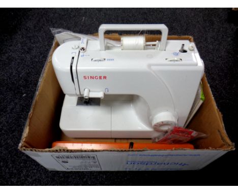 A box containing a Singer electric sewing machine with foot pedal and instruction manual together with sewing accessories and