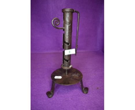 A wrought iron candle stick on tripod base