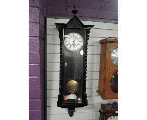 An enamel faced wall clock having single weight pendulum