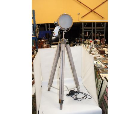 A CHROME TELESCOPIC STYLE SPOT LIGHT ON A WOODEN TRIPOD BASE