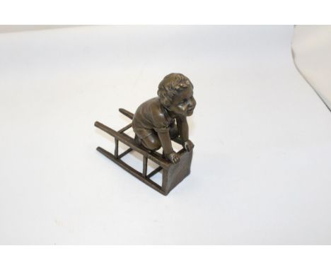 A BRONZE FIGURE OF A CHILD ON A CHAIR - SIGNED