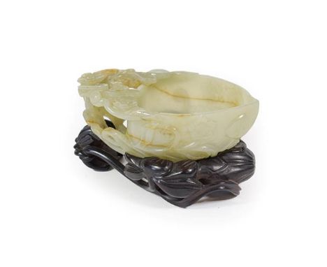 A Chinese Jade Libation Cup, in the form of a peach with pierced foliate scroll handle, 12cm long, on hardwood base CONDITION