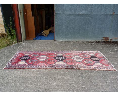 A carpet Runner with hexagonal patterns in red and cream, some fading, 112'' x 41''.