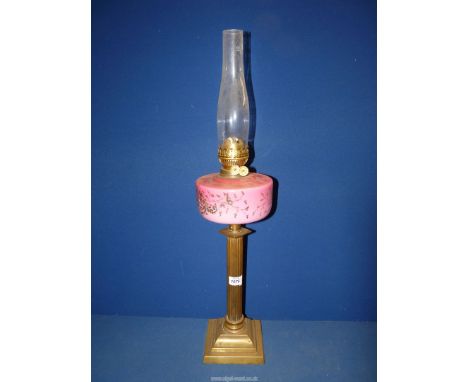 An Oil lamp on brass square base with reeded column supporting a pink glass reservoir with floral detail, with chimney, no sh