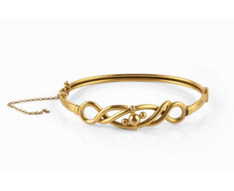A late 19th/early 20th century bangle, of hinged oval hollow design, with knot and bead frontispiece, stamped '9CT' and signe