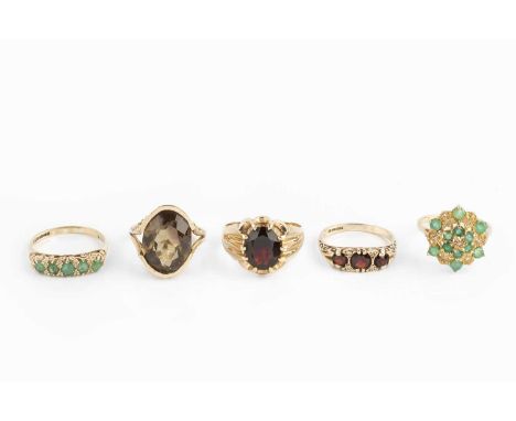 Five gem set dress rings, comprising a garnet and diamond half hoop ring, a garnet single stone ring, an emerald and diamond 