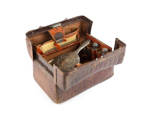 A late Victorian crocodile skin dressing case, the fitted interior containing a range of silver and silver mounted accessorie