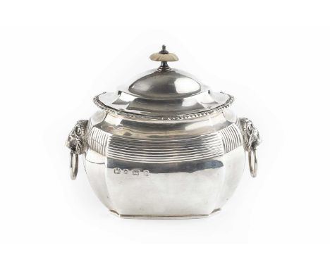 A George V silver tea caddy, of shaped and faceted oval form, with gadrooned border, reeded body, and lion's mask ring handle
