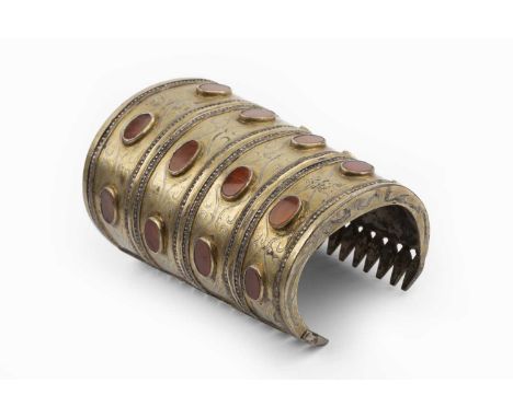 An Eastern cuff bangle, of tapered design, decorated with oval agate slices, scrolls and beaded borders, length 10.7cmConside