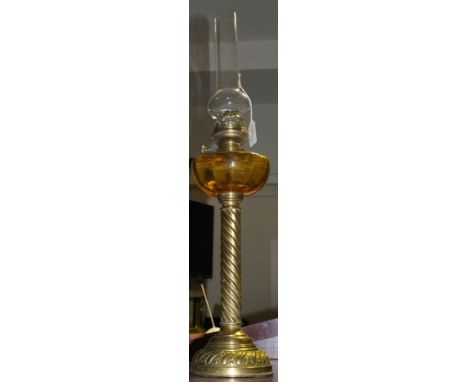 A late 19th Century French brass oil lamp, with amber glass reservoir over barley twist stem, the base with embossed decorati