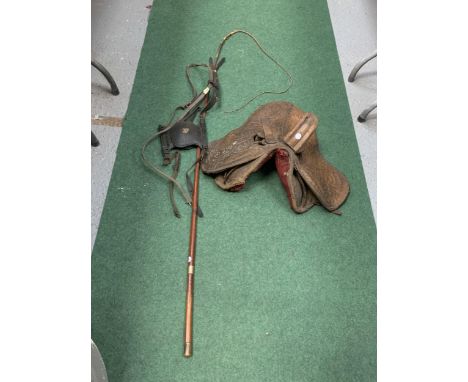 A SMALL VINTAGE DRESSAGE SADDLE, A BRIDLE WITH BLINKERS AND A LONG WHIP 