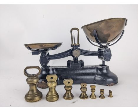 Libra Scale Co black painted cast iron scales with brass pans, and a graduated set of seven bell shaped weightsLocation: 