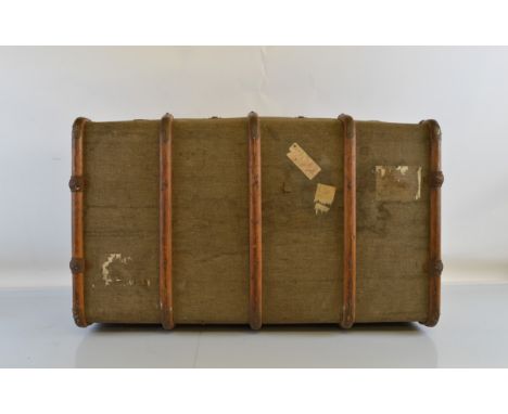 A 1930s or 40s bound trunk, having moulded wooden banding and metal bracket supports, some paper labels, leather carrying han