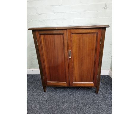 A contemporary mahogany cabinet, having double doors opening to two shelf interior and two division bottom section on taperin