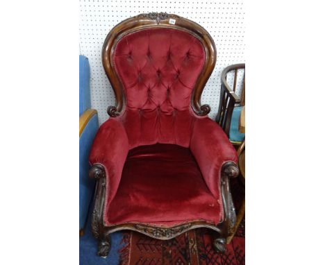 A Victorian mahogany framed upholstered and button backed armchair with carved frame.
