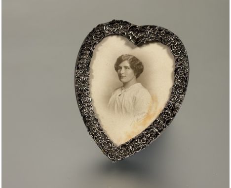 An Edwardian Birmingham silver heart shaped mounted photograph frame with floral and leaf chased border on easel stand Birmin