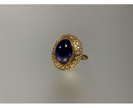 A 9ct gold dress ring set oval cabouchon amethyst in etruscan style with bead and rope border, approximatly 5.ct: O 6.53g 