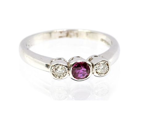 A ruby and diamond platinum three stone ring, comprising a central round cut ruby set either side with a brilliant cut diamon