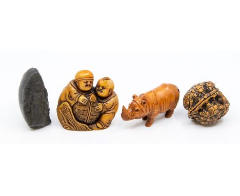 A carved treen netsuke, as a rhino, approx 7cm long; a carved walnut; a fossilised tooth carved depicting a deity, approx 6cm