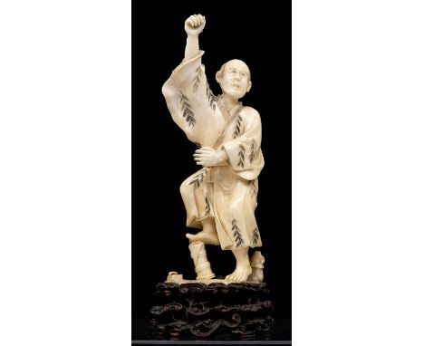 A Japanese Meiji period carved ivory Okimono of a man holding a (missing) item aloft, right foot balancing on bamboo, his rob