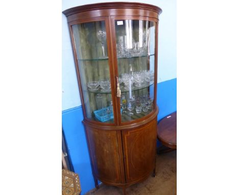 An Edwardian Demi Lune Glaze Fronted Display Cabinet, the glazed front with two internal glass shelves rests above a single c