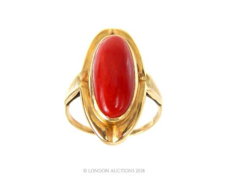 An 18 ct yellow gold, and deep-red coral, elongated ring, the oval-shaped yellow gold mount to wide shoulders and slender rou