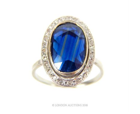 A platinum, French, vintage, large oval sapphire and diamond ring, the elongated, faceted sapphire surrounded by a halo of br