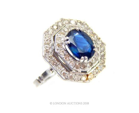 A platinum, Art Deco, French, diamond and sapphire ring composed of a central, claw set, faceted sapphire surrounded by an oc
