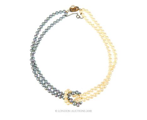 A vintage, doubled strand of fine, half white and half grey, cultured pearls terminating in a stylish pearl knot, with a silv