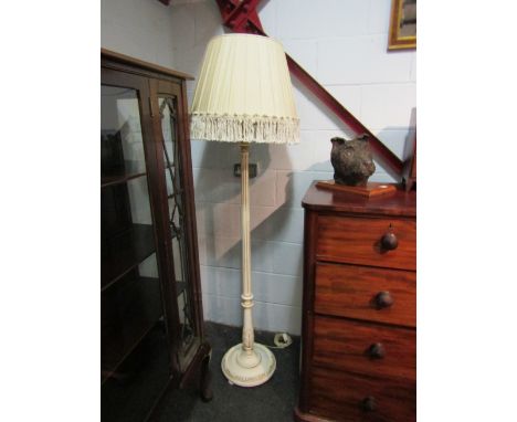 A cream and gold painted standard lamp with tasseled shade
