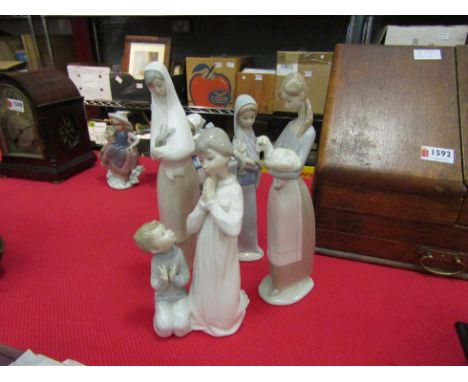Three Lladro figurines and a figural group: young lady with rabbit, girl with lamb, girl with lilies and children playing