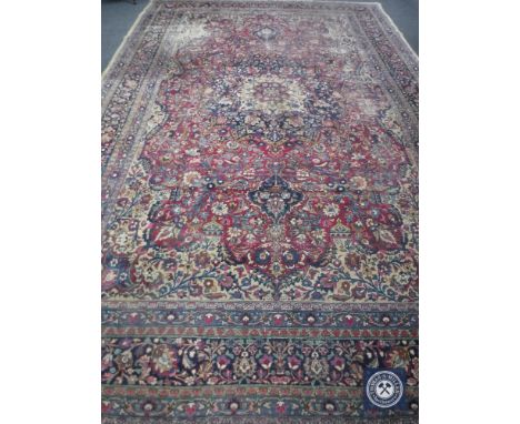 An antique Tabriz carpet, Iranian Azerbaijan, with a deep raspberry central field of floral vines around an indigo medallion,