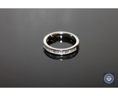 An 18ct white gold diamond half-eternity ring, set with twenty-one baguette-cut stones within a channel setting, to a plain s