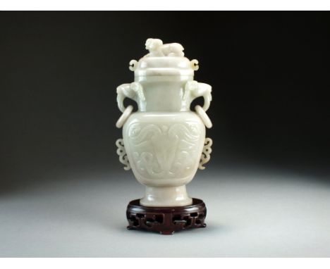 A Chinese nephrite jade vase and cover, 19th/20th Century, of baluster form with twin ram's head and ring handles, the domed 