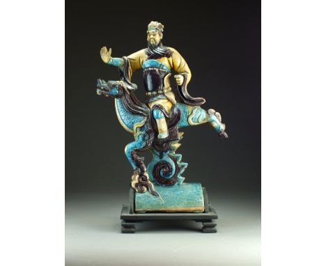A Chinese sancai glazed pottery roof tile, Qing Dynasty, modelled as a guardian figure riding a kylin, decorated with turquoi
