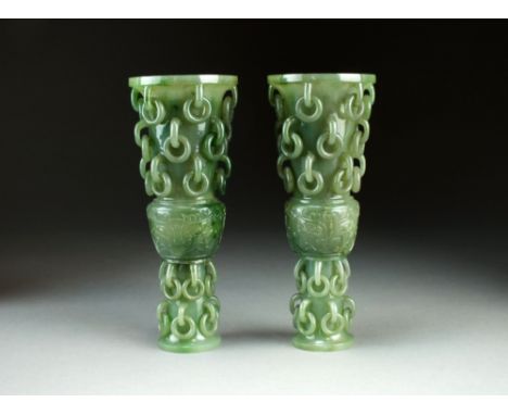 A pair of jade Gu form vases, Qing Dynasty, the centre sections carved with taotie masks, the necks and feet carved with mult